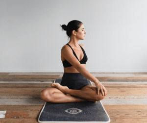 Frau praktiziert Yoga auf einer Matte um ihre Darmbewegung anzuregen