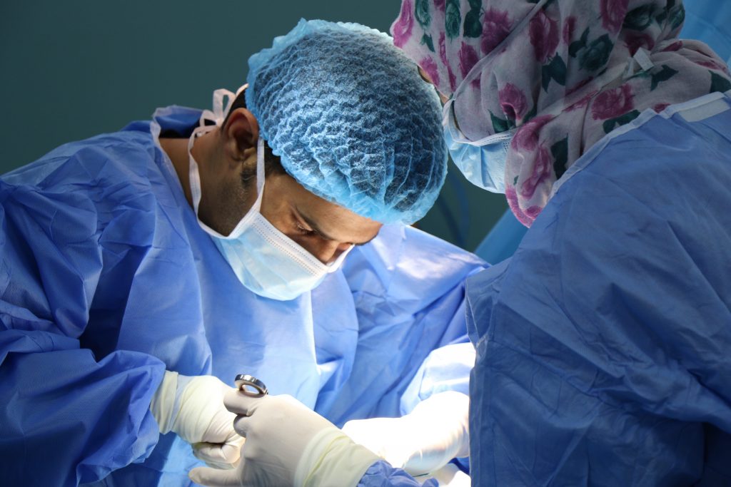 Arzt und Helfer am OP Tisch bei Durchführung einer Operation